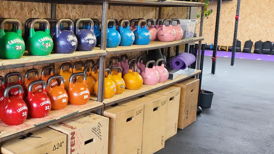 De plank met kettlebells in alle kleuren en gewichten, met plyoboxen eronder
